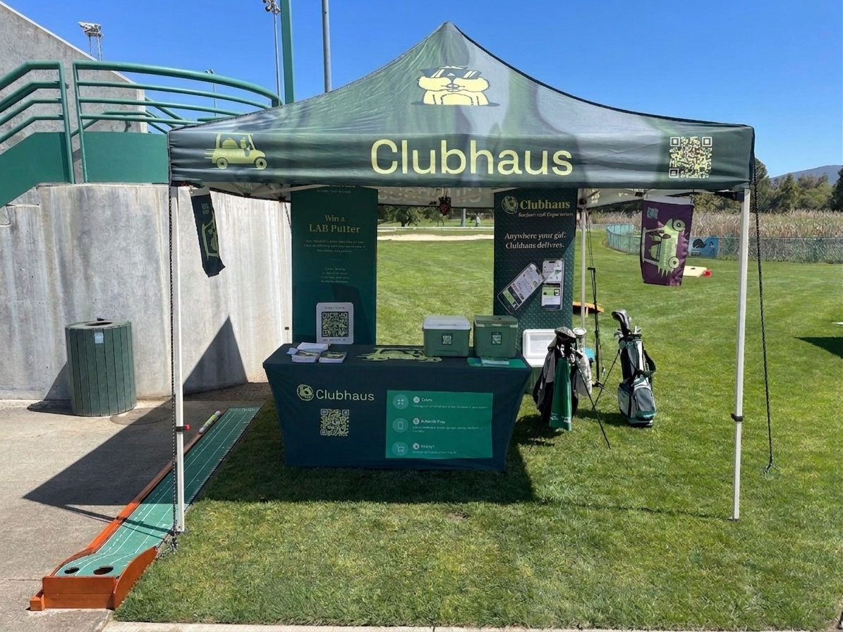 Branded Clubhaus activation tent with a putting strip, table cover, and signage set up on a golf course