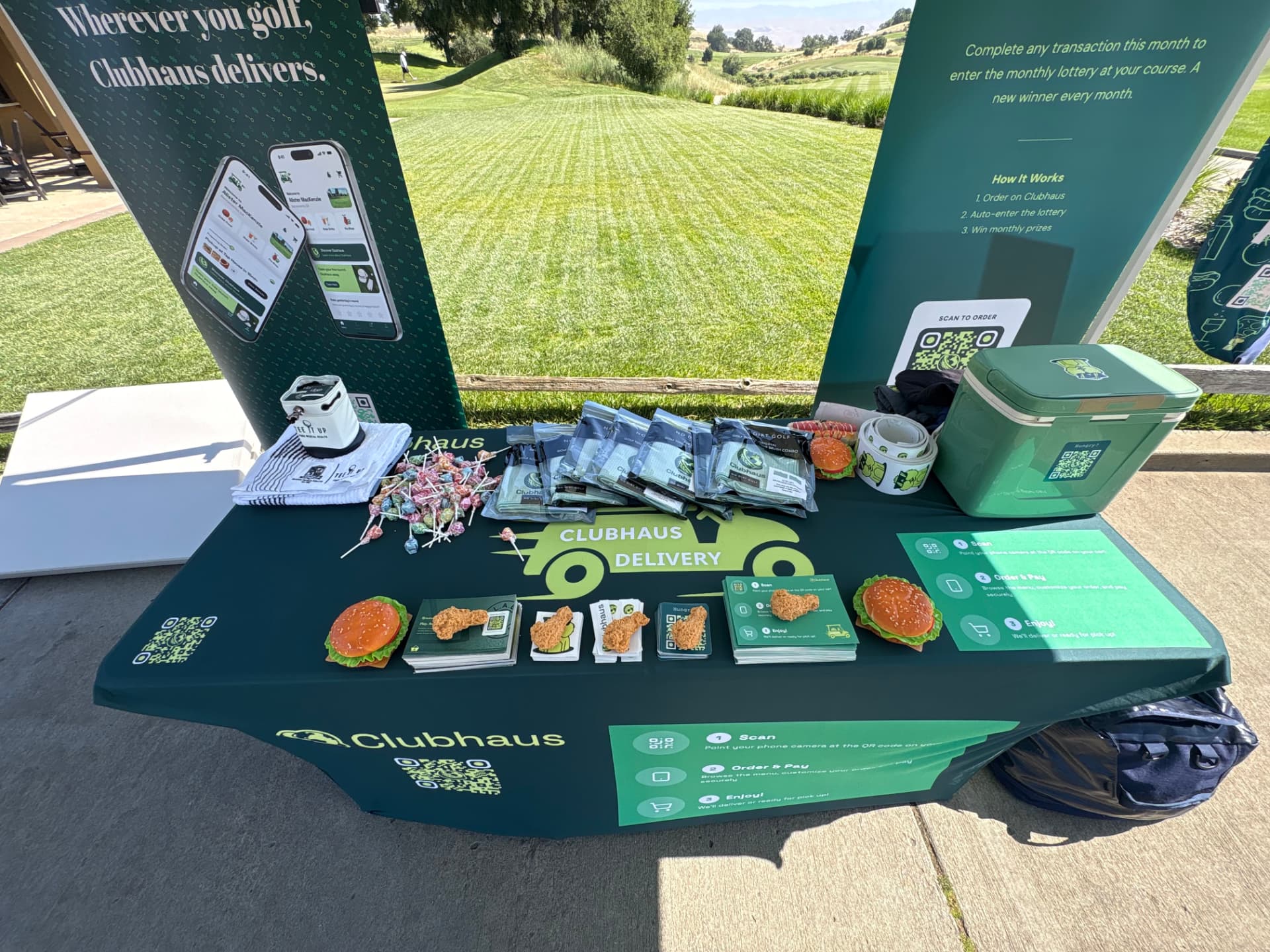 Clubhaus table display with branded towels, snacks, cooler, and QR cards