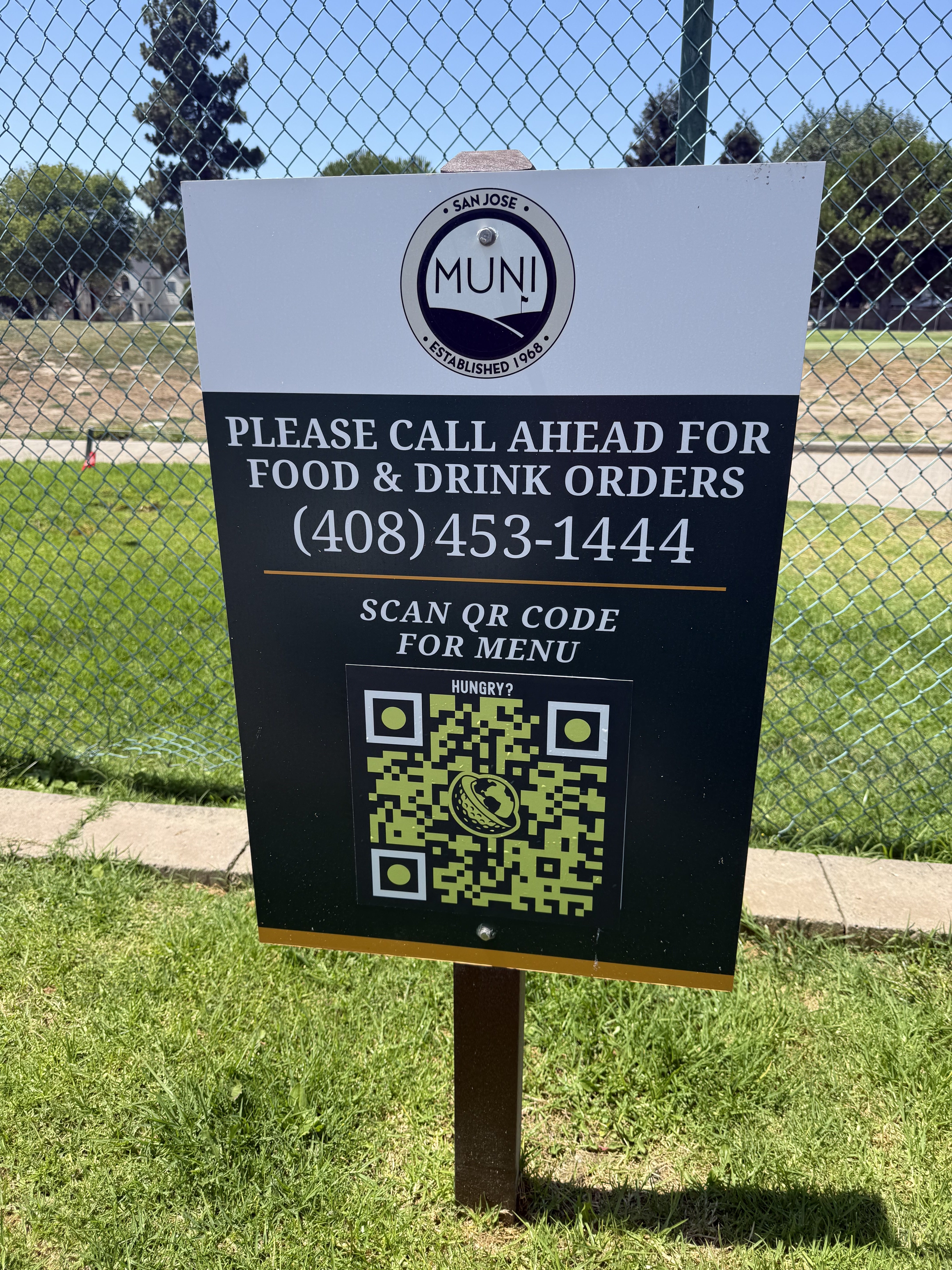 On-course sign with a QR code for food and drink orders mounted on a fence